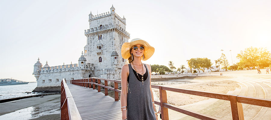 Turista joven caminando sobre el puente de la torre de Belem en la orilla del río durante la puesta de sol en Lisboa, Portugal.